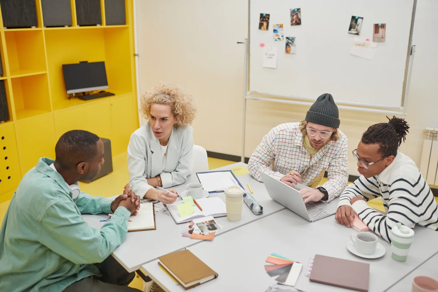 Four colleagues working together around a laptop and workshop materials